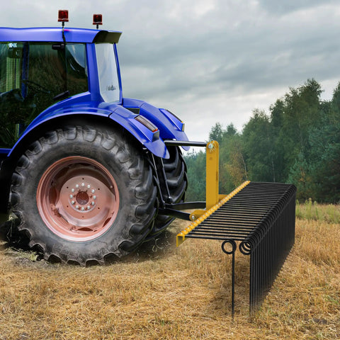 72 Inch Tow Behind Landscape Rake with 32 Steel Tine Dethatcher for Category 1 Tractors attached to a blue tractor on a field