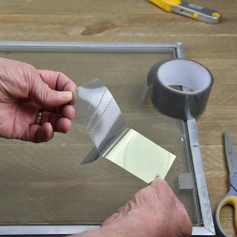 Screen Repair Patch Kit With Fiberglass Mesh And Strong Adhesive For Window And Door Screens being applied to a screen frame
