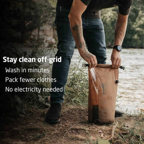 Compact Travel Laundry Washbag Featuring Patented Flex Washboard Design For Machine Grade Dirt Removal Without The Laundromat Hustle On Road Trips Camping Adventures Or Hotel Hops, being used by a camper to wash clothes by a river.