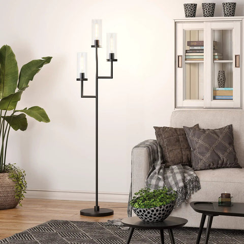 Three Light Torchiere Floor Lamp With Glass Shades In Blackened Bronze And Clear Finish beside a sofa in modern living room.