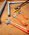 Three Piece Adjustable Cushion Grip Wrench Set With 6 Inch, 8 Inch And 10 Inch Jaw Wrenches on wooden table with pipes