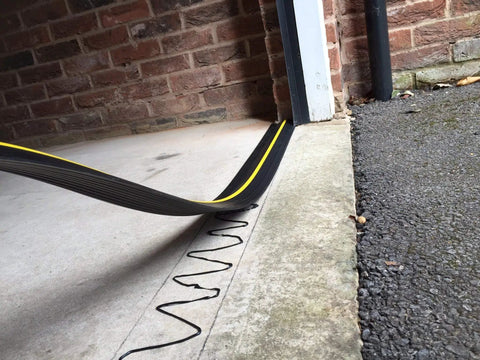 Weatherproof Garage Door Threshold Floor Seal 18 Foot Eight Inch Long Keeps Water Out Vermin Leaves And Debris From Blowing Under Your Door With Anti Slip Ridges High Visibility Safety Line And Easy Installation shown during installation
