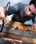 Close-up of a black rotary tool held in hand, sparks flying as metal is ground.
