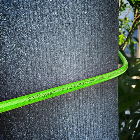 Close-up of green Flexible One Quarter Inch 100 Foot Reinforced PU Air Hose With Fittings And Plug Kit wrapped around a post