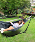 Person relaxing on 2 In 1 Hammock And Swing Chair With Collapsible Steel Stand And Carrying Case Portable And Adjustable in garden