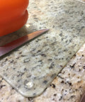 Glass cutting board on granite with 100 Clear Cabinet Door Bumpers Half Inch Self Adhesive Rubber Feet Pads visible underneath.