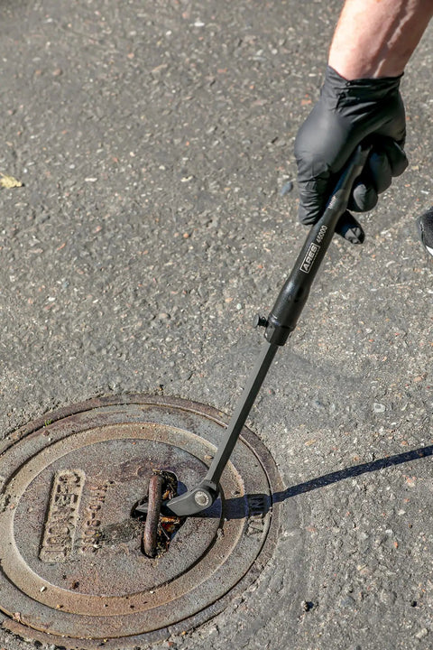 Extendable Pry Bar With 13.3 To 18.5 Inch Reach 14 Position Adjustable Angled Head lifting a manhole cover