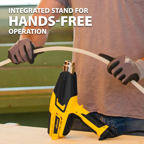 Person using FURNO 700 Digital Heat Gun With 2 Nozzles for bending PVC pipe, showing hands-free operation with integrated stand.