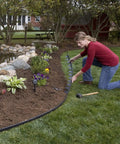 Person installing 40 Foot Flexible Plastic Garden Edge Roll With 40 Spikes Two Inch Tall No Dig Landscape Border along flower bed.