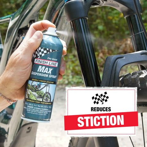 Person using Max Suspension Spray For Bicycles A Premium Lubricant For Forks And Shocks That Revives Old Suspension, 9 Fl Oz, on bike fork