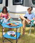Folding Camping Table Lightweight Double Layer Round Table With 4 Cup Holders And Carry Bag Portable Beach Table For Camping Travel Fishing And Outdoor Activities Blue in use at a campsite.