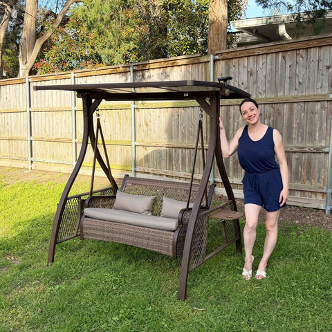 Patio Porch Swing Chair For Two With Canopy Handwoven Wicker Outdoor Glider With Solar LED Light Cushions shown in backyard