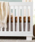 Modo 3 In 1 Baby Crib That Converts To Toddler Bed And Daybed Includes Toddler Conversion Kit Solid Wood Crib For Baby With Four Adjustable Heights White GREENGUARD Gold Certified with a beige blanket draped over the side