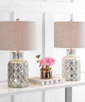 Alvord Mercury Silver Quatrefoil Glass Table Lamps Set of 2 with grey drum shades on a console table beside decor items.