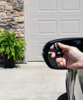 Hand holding Single Button Garage Door Opener Remote for Intellicode Compatible Openers near car mirror