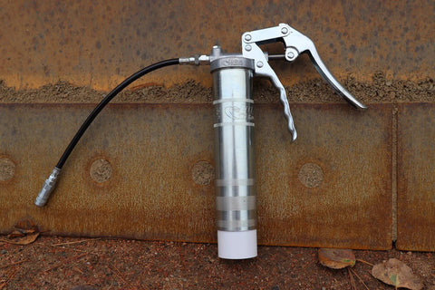 One Hand Pistol Grip Grease Gun Kit with SafeLock Coupler and Zinc Plated Barrel on rusted metal surface