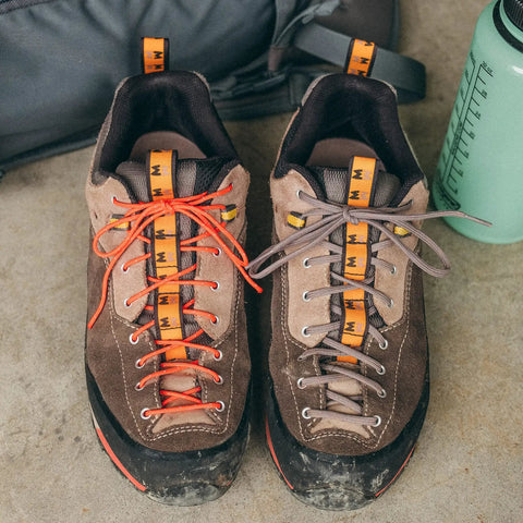 Two hiking shoes with Paracord 175 Lightweight Visible Guyline For Tents And Tarps Reflective Orange 100 Ft as shoelaces.