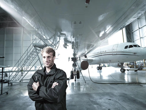 Aircraft maintenance engineer standing under airplane in hangar.