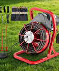 Automatic Feed Electric Drain Snake Auger With Seventy Five Foot Steel Core Cable on grass, includes tools and gloves for clogs.