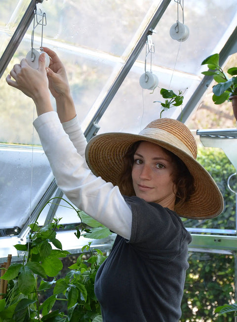 Woman using Trellising Kit Pro for Canopia Greenhouses with Six Roller Hooks and 25m Twine to support plants