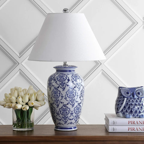 Chinoiserie Blue And White Ceramic Table Lamp With Urn Silhouette, Traditional Asian Inspired Living Room Or Bedroom Lighting, White Linen Shade, LED Bulb Included, ETL Listed For Safety on wooden table with books and flowers