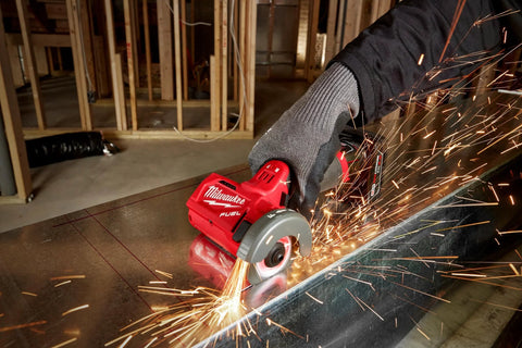 Milwaukee 12V cut-off tool, red with gray guard, cutting metal as sparks fly in workshop