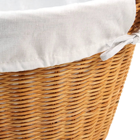 Close-up of rattan laundry basket with easy carry handles and removable white cotton liner, natural wicker texture visible.
