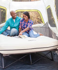 Couple sitting on Queen Size Airbed Cot With Folding Steel Frame And Side Table Battery Pump Included Portable Camping Bed For Indoor Outdoor Use