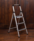 Lightweight Aluminum 3 Step Ladder With Wide Non Slip Steps Foldable Stepladder For Kitchen Pantry Closets And Home Office Space Saving Indoor Use Handy Portable Step Stool Durable Silver Finish, folded open on wood floor