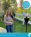 Woman holding Conical Bronze Outdoor Torch Set For Backyards And Patios, Weather Resistant, installed in garden, lit during evening