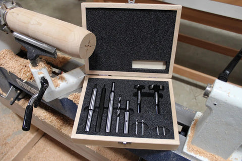Premium Four Piece Forstner Bit Set Built For No Headache Splinter Free Cuts displayed in wooden case on wood lathe.