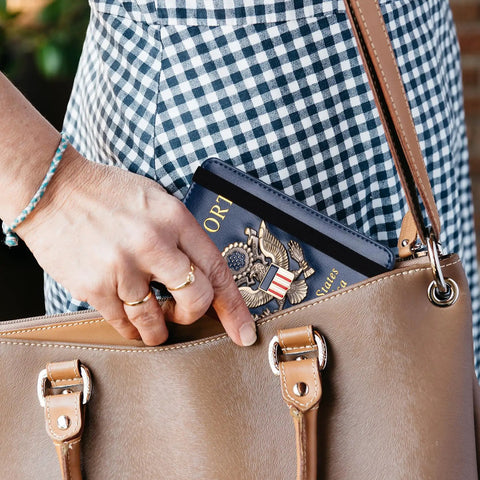 Person placing passport in RFID Blocking Leather Passport Holder Travel Wallet For Women And Men, Dark Blue in a handbag.