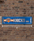 New York Knicks Metal Street Wall Sign Four By Fifteen Inches Heavy Duty Aluminum Game Day Home Office Man Cave Decor on brick wall.