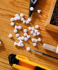 Three Sixteenth Inch Plastic Hole Plugs For Round Holes scattered on a wooden surface with tools and a transparent box visible