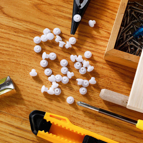 Three Sixteenth Inch Plastic Hole Plugs For Round Holes scattered on a wooden surface with tools and a transparent box visible