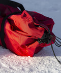 Heavy Duty Pop Up Insulated Ice Fishing Shelter With Knockout Spacious Fishin Spot For Five To Seven Crews Quick Roll Setup Trip Proof Door Wide Flared Bottom Red Black 94 Square Feet rolled up on snow