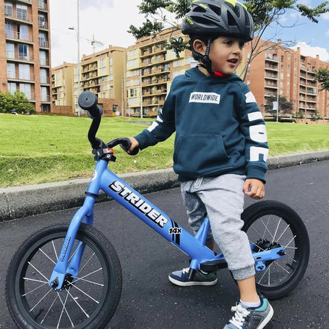 Child riding a blue Strider balance bike with Performance Seat With XL Post For 12 And 14X Balance Bikes Extends Seat Height From 15 To 19 Inches Quick No Tool Assembly Keeps Up With Tall Kiddo Riders And Grows With Your Little Cyclist outdoors.