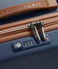 Close-up of Delsey 26-inch spinner luggage with TSA lock and navy textured design, featuring faux leather accents and durable zippers.