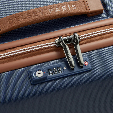 Close-up of Delsey 26-inch spinner luggage with TSA lock and navy textured design, featuring faux leather accents and durable zippers.