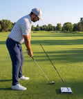 Golfer using Golf Swing Trainer Cube With 12 Adjustable Club Positions, Guided Strikes Tool, Alignment Rods on green field