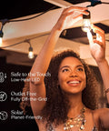 Person smiling while adjusting Solar Powered Outdoor String Lights 48 Ft Edison Bulbs Shatterproof LED on patio.