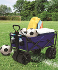 Heavy Duty Collapsible All Terrain Utility Wagon Cart For Beach Adventures With Large Interior No Assembly Required Grab And Go Setup Foldable Beach Wagon Portable Outdoor Gear Cart With Carry Case And Oversized All Terrain Wheels loaded on a grassy field with soccer balls, cooler, and bag, showcasing its storage capacity.