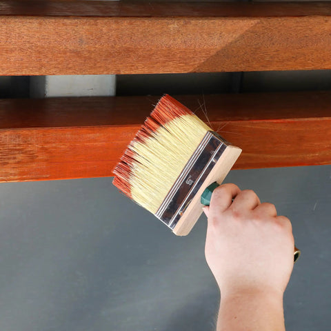 Hand holding deck stain brush set with red handle three size set with 4 inch 5 inch and 6 inch for tight corners and wide decks