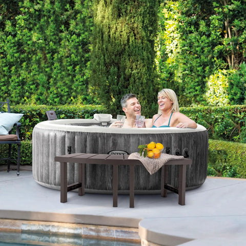 Two Pack PureSpa Accessory Benches For Four Person Spas next to a hot tub with towels and drinks on top, garden view