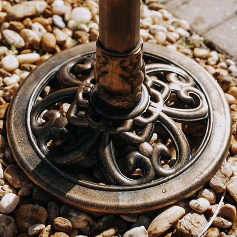 Base of Bronze Outdoor Garden Bird Bath With Ground Stakes on gravel, showing weather resistant resin, part of sturdy three-stake base