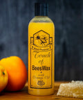 Bottle of Beeswax Wood Polish And Restorer Bundle For Hardwood Floors with orange oil and wax, 16 oz size, next to oranges