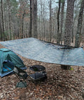 No Nonsense Tough 9 Mil Tarp Cover Waterproof UV Resistant Tarpaulin set up as canopy over camping area in forest