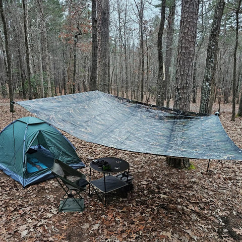 No Nonsense Tough 9 Mil Tarp Cover Waterproof UV Resistant Tarpaulin set up as canopy over camping area in forest