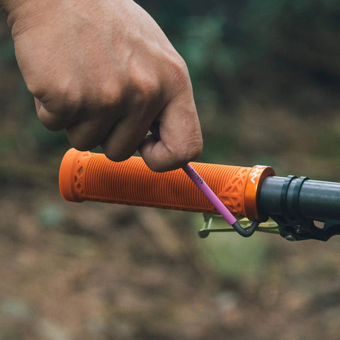 Close-up of orange Lock On Clamp Mountain Bike Handlebar Grips With Lightweight Ergonomic Design being installed on a bike