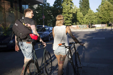 Two people walking bicycles in an urban area, suitable for using Beefed Up Heavy Duty 12mm Hardened Manganese Steel Bike Chain Lock